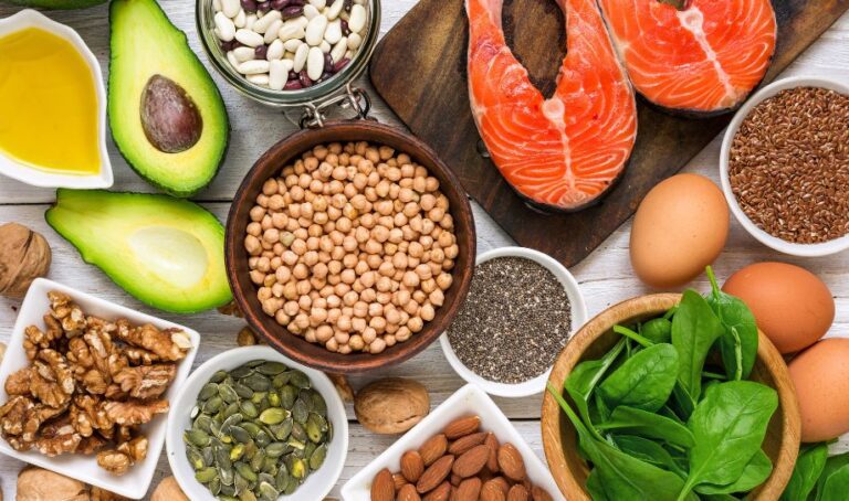 A tabletop view of a spread of nutritionist approved healthy food including avocado, salmon, almonds, and more
